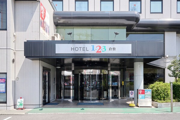 A hotel entrance with a revolving door, a sign indicating the hotel name and number, and a small signboard with information. - Hotel 1-2-3 Kurashiki (Kurashiki)