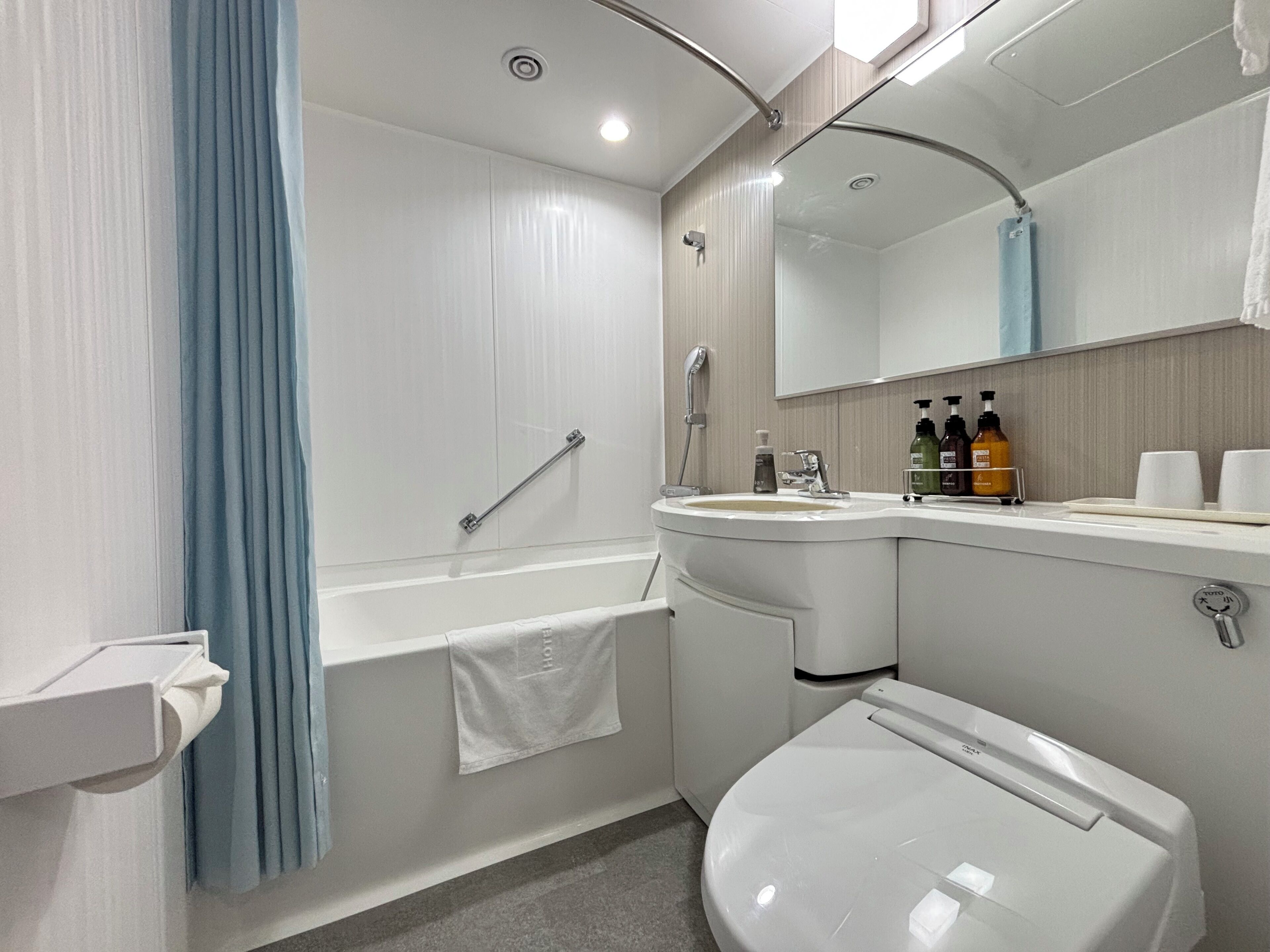 A modern bathroom with a bathtub, toilet, sink, and a large mirror.