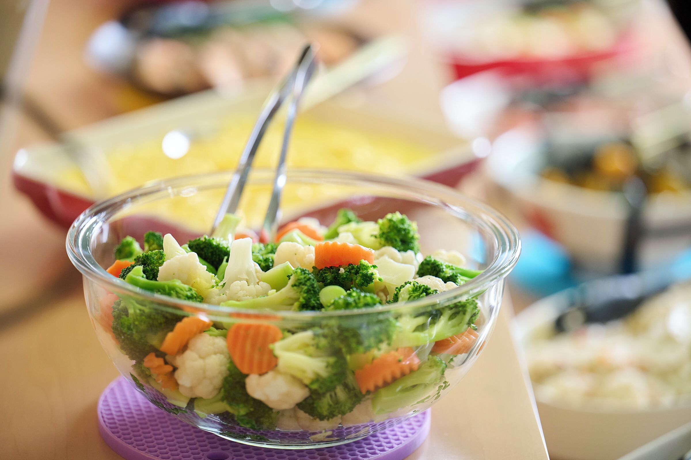 Un tazón de vidrio transparente lleno de una ensalada de verduras variadas.