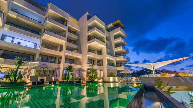 A modern hotel with a rooftop infinity pool, multiple balconies, and outdoor seating areas. - Sansuri Resort Phuket (Choeng Thale)