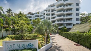 A multi-story hotel with a modern design, featuring balconies and a well-maintained garden area. - Sansuri Resort Phuket (Choeng Thale)