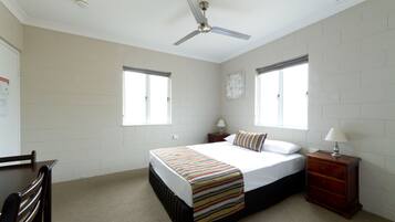 A bedroom with a bed, nightstands, a wooden dresser, and a ceiling fan.