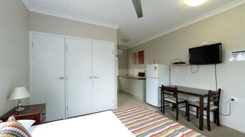 A hotel room with a bed, a desk, a chair, a television, a microwave, and a refrigerator.