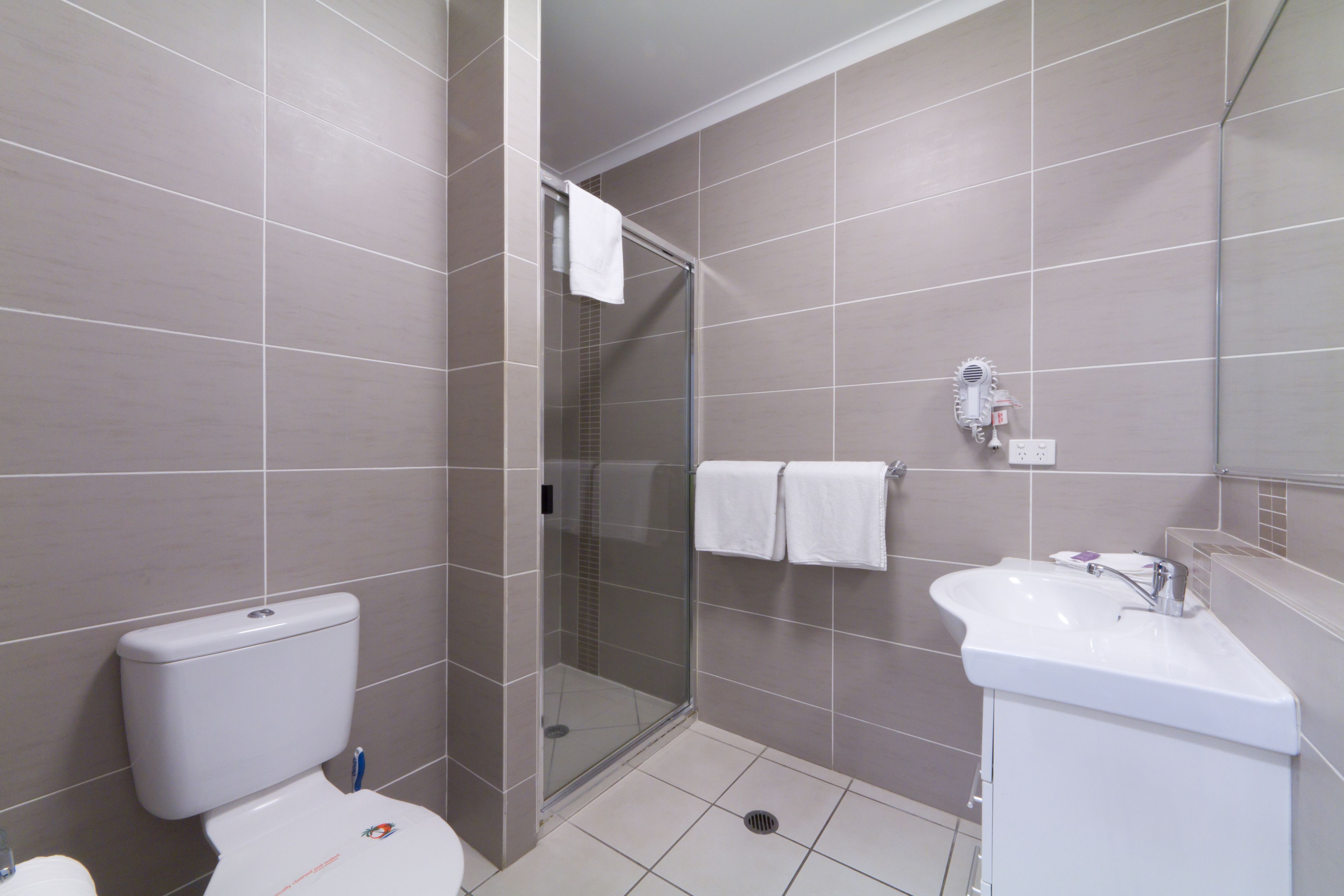 A modern bathroom with a toilet, a glass-enclosed shower, and a sink.