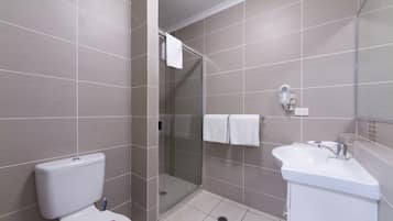 A modern bathroom with a toilet, a glass-enclosed shower, and a sink.