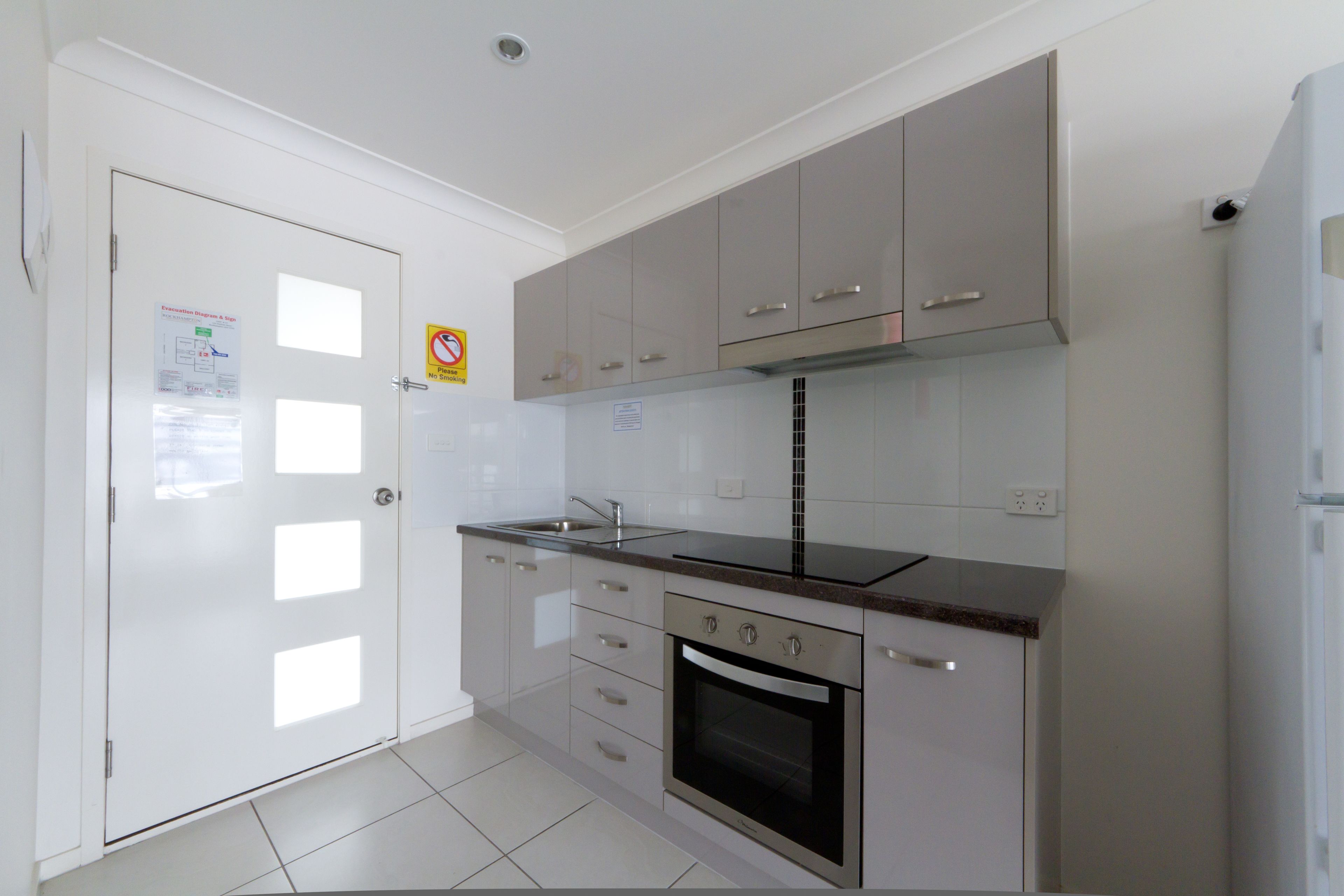 A modern kitchen with white cabinets, a stainless steel oven, and a black countertop.