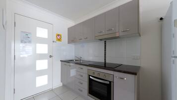A modern kitchen with white cabinets, a stainless steel oven, and a black countertop.