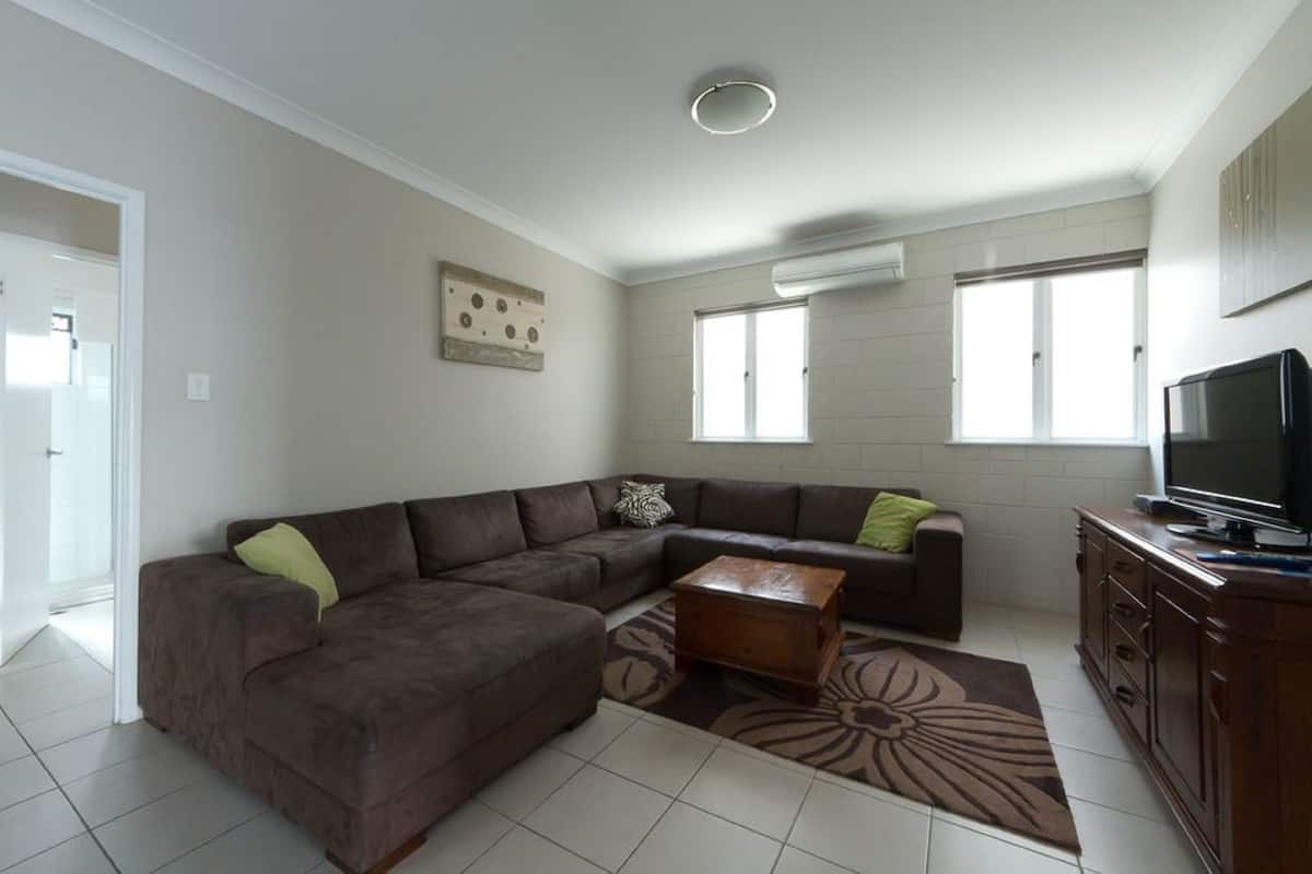 A living room with a brown sectional sofa, a wooden coffee table, and a TV on a wooden cabinet.