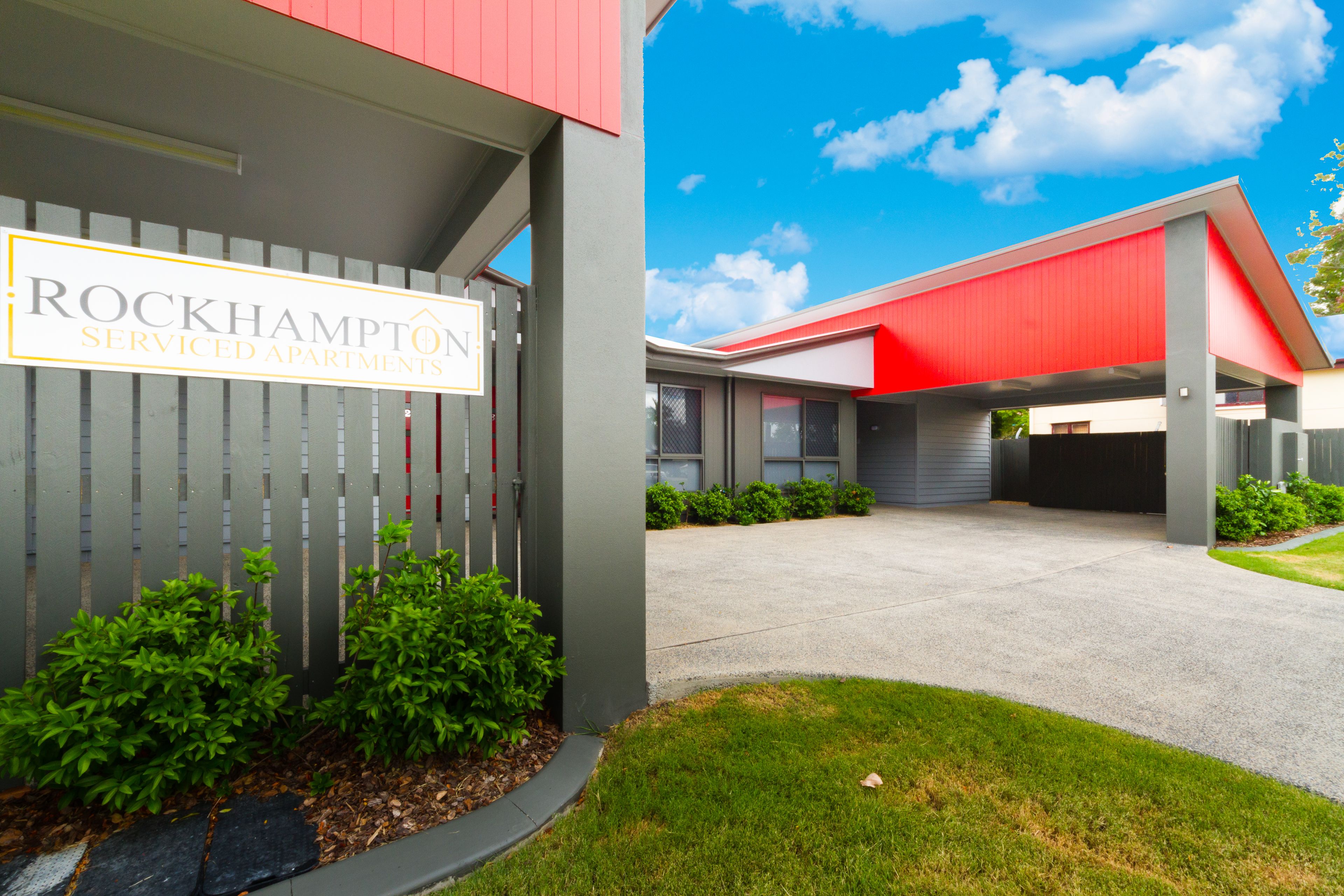A building with a sign reading "Rockhampton Serviced Apartments."