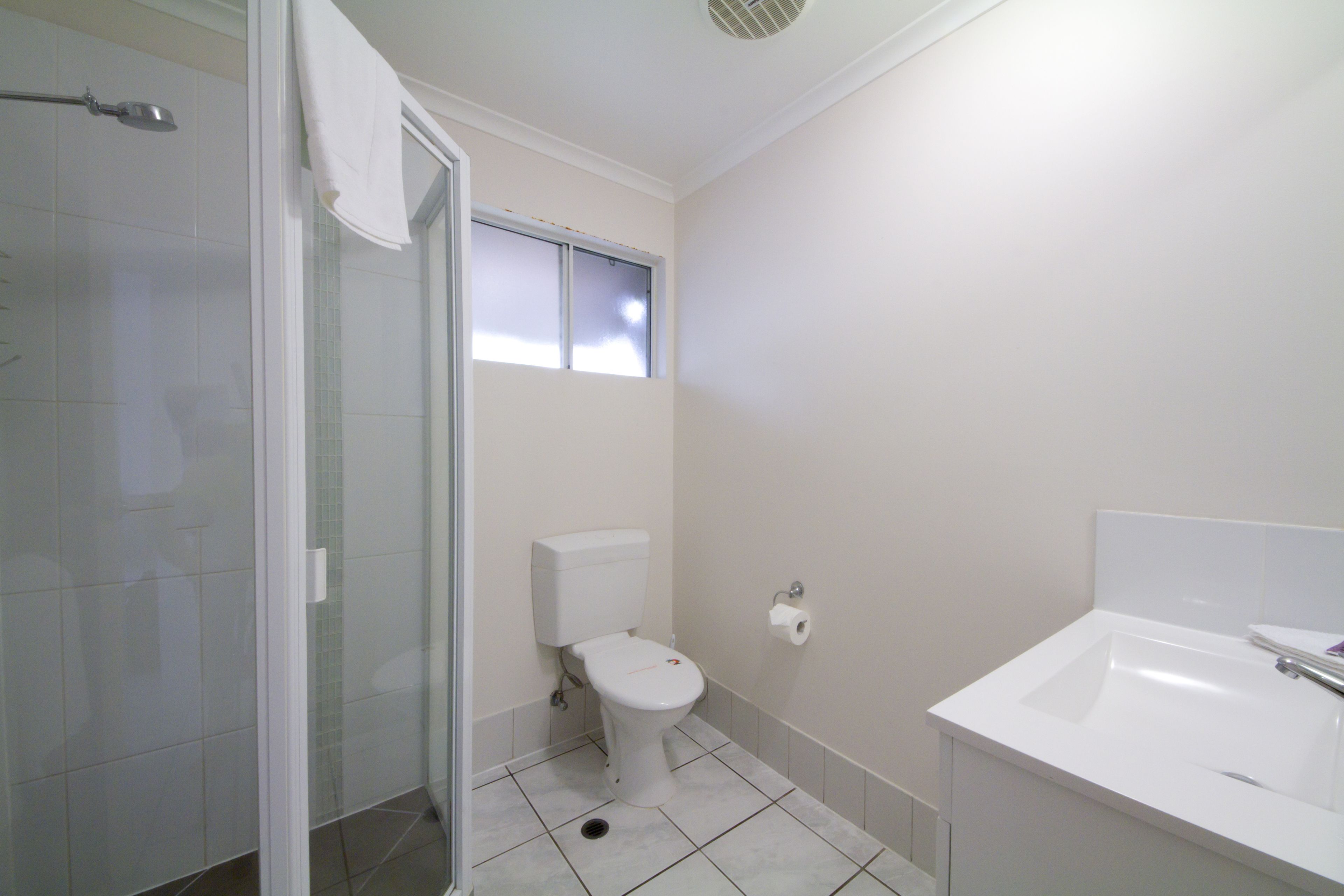 A bathroom with a toilet, a shower, and a sink.