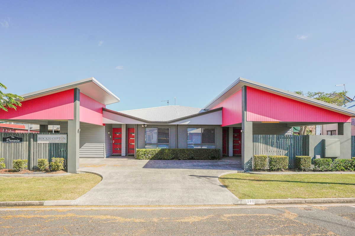 A building with a red facade, a central entrance, and a clear sky.