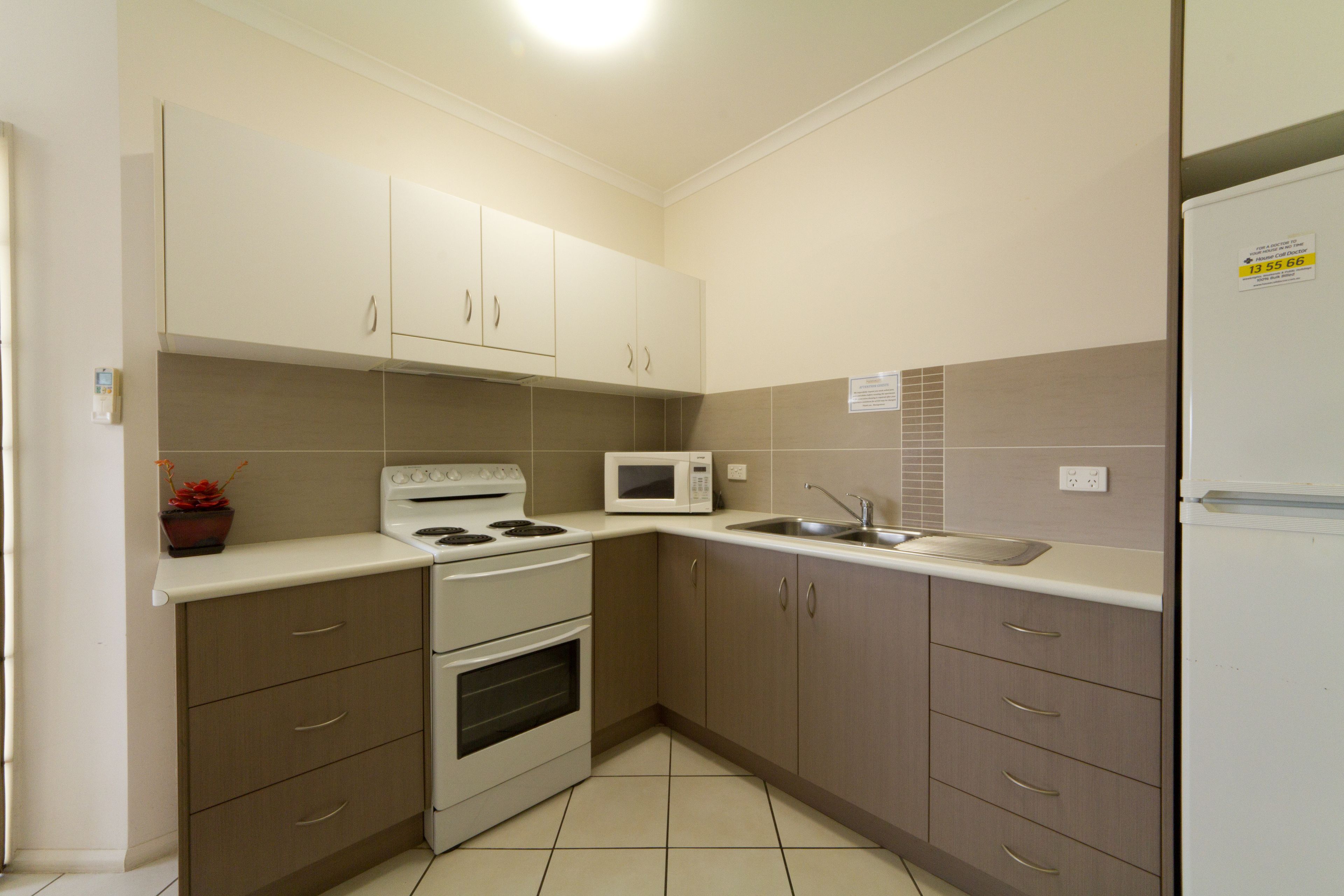 A compact kitchen with white cabinets, a microwave, a stove, and a sink.