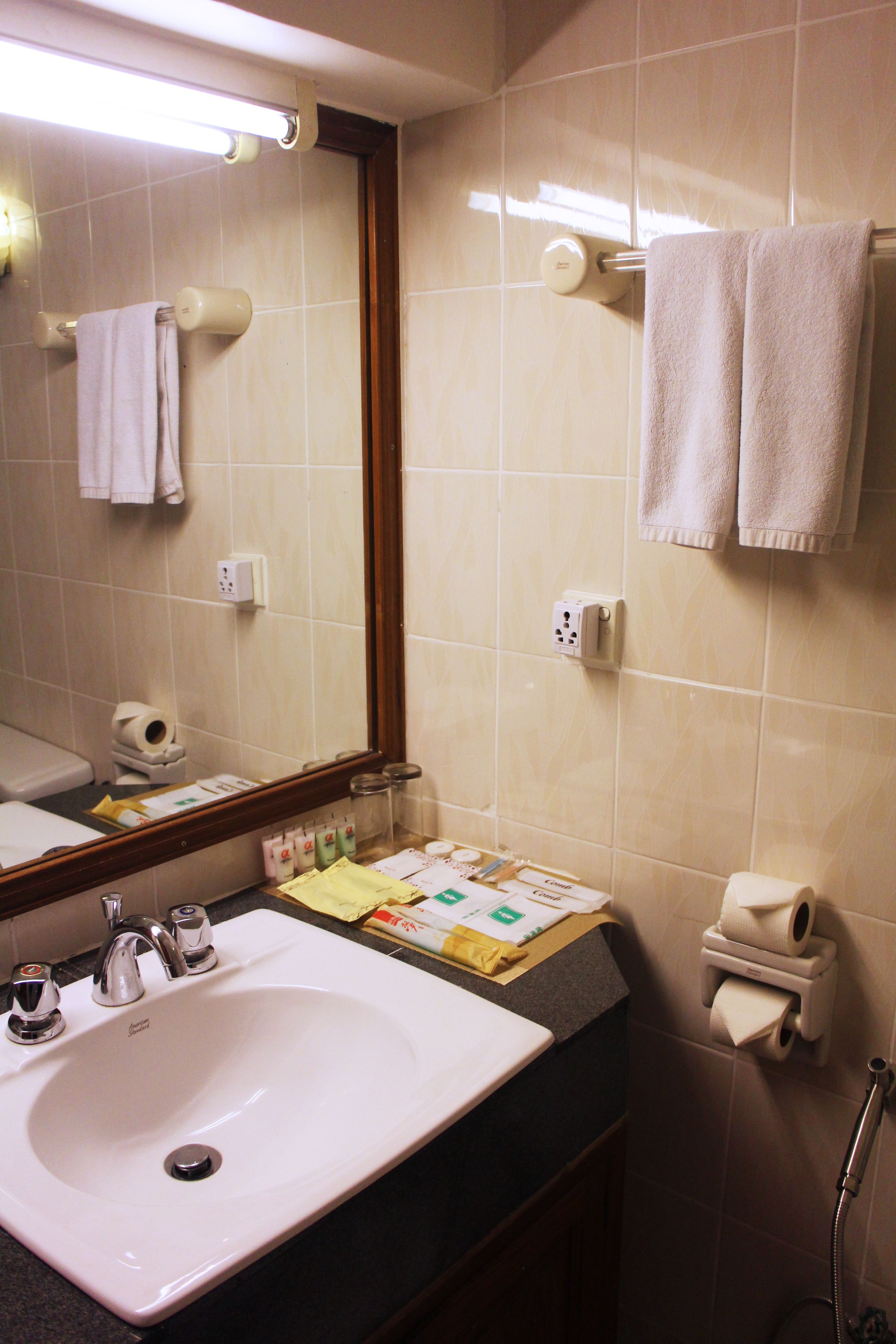 A bathroom with a sink, mirror, towel rack, and toiletries.
