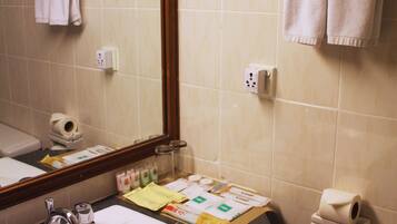 A bathroom with a sink, mirror, towel rack, and toiletries.
