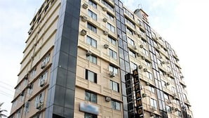 A multi-story hotel with a modern facade, featuring a prominent vertical sign indicating its name.