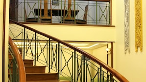 A wooden staircase with green metal railings leading to an upper floor.