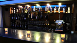 A bar area with shelves of liquor bottles, glasses, and a coffee machine.