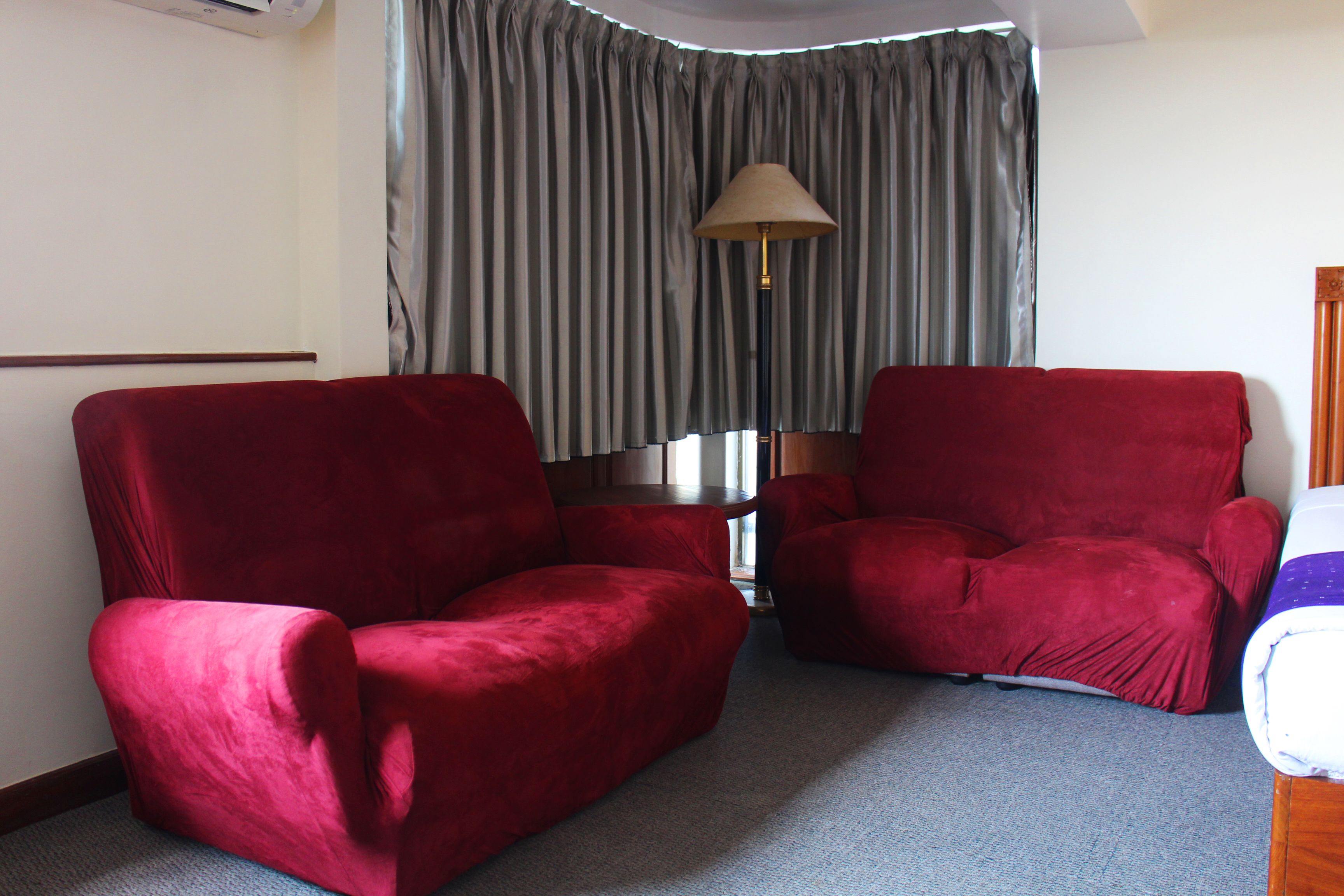 Una habitación con dos sillones rojos y una lámpara.