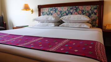 A neatly made bed with a floral headboard, a bedside lamp, and a telephone on the nightstand.
