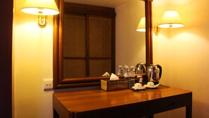 A hotel bathroom with a wooden vanity, a large mirror, and two wall-mounted lamps.