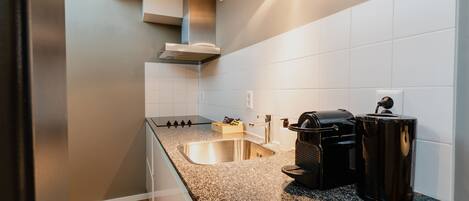 A modern kitchen with a granite countertop, stainless steel sink, and black appliances.
