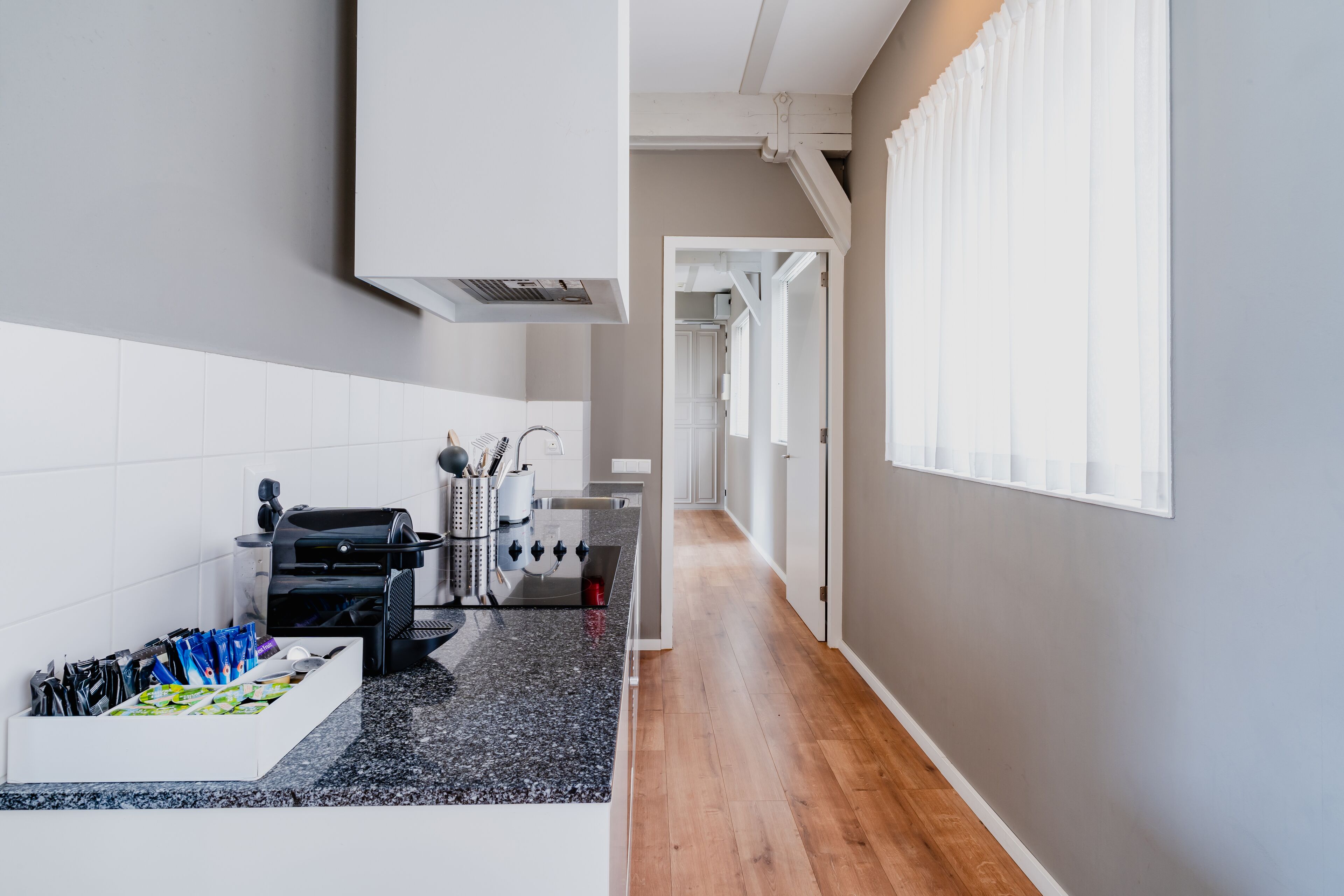 A modern kitchen with a black granite countertop, white cabinetry, and a built-in oven.