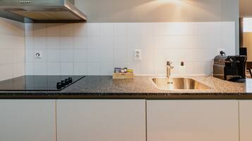 Una cocina moderna con un lavamanos de acero inoxidable, horno empotrado y extractor de humos.