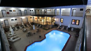 Un hotel con piscina, diversi balconi e zone salotto all'aperto.