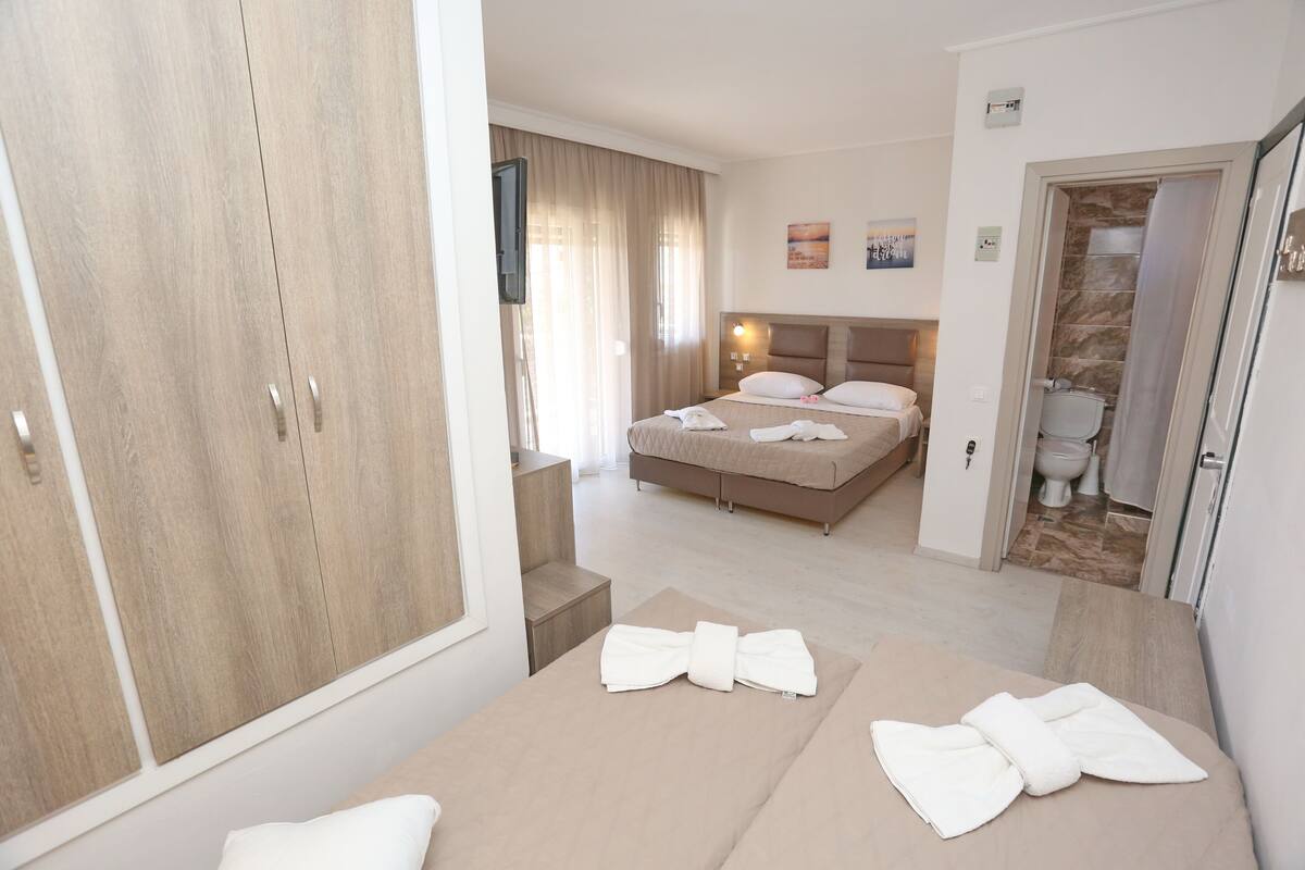 Una camera d'albergo con un letto, un armadio, un bagno e una televisione.