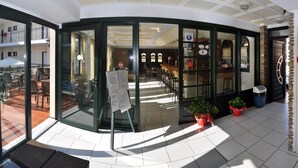 L'ingresso di un hotel con una porta in vetro, una reception e una sala da pranzo visibile attraverso il vetro.