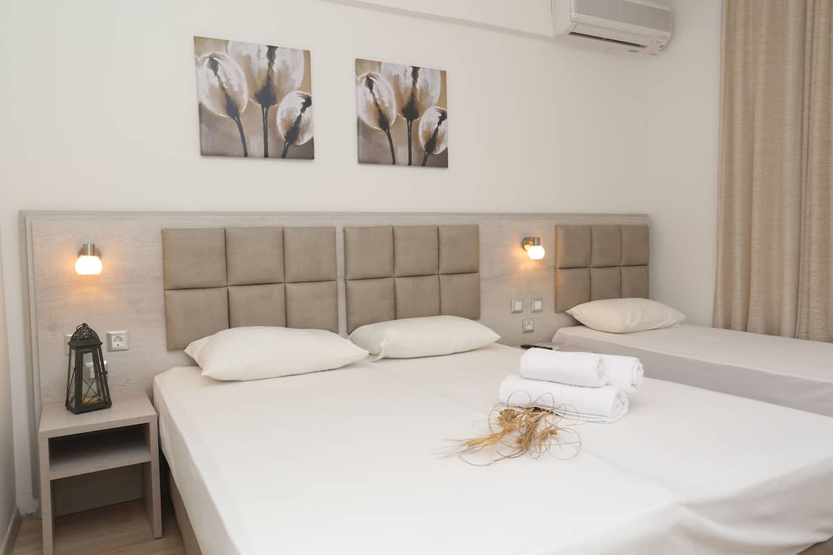 Camera d'albergo con un letto grande, due quadri appesi al muro, un comodino con una lanterna e un condizionatore d'aria a parete.