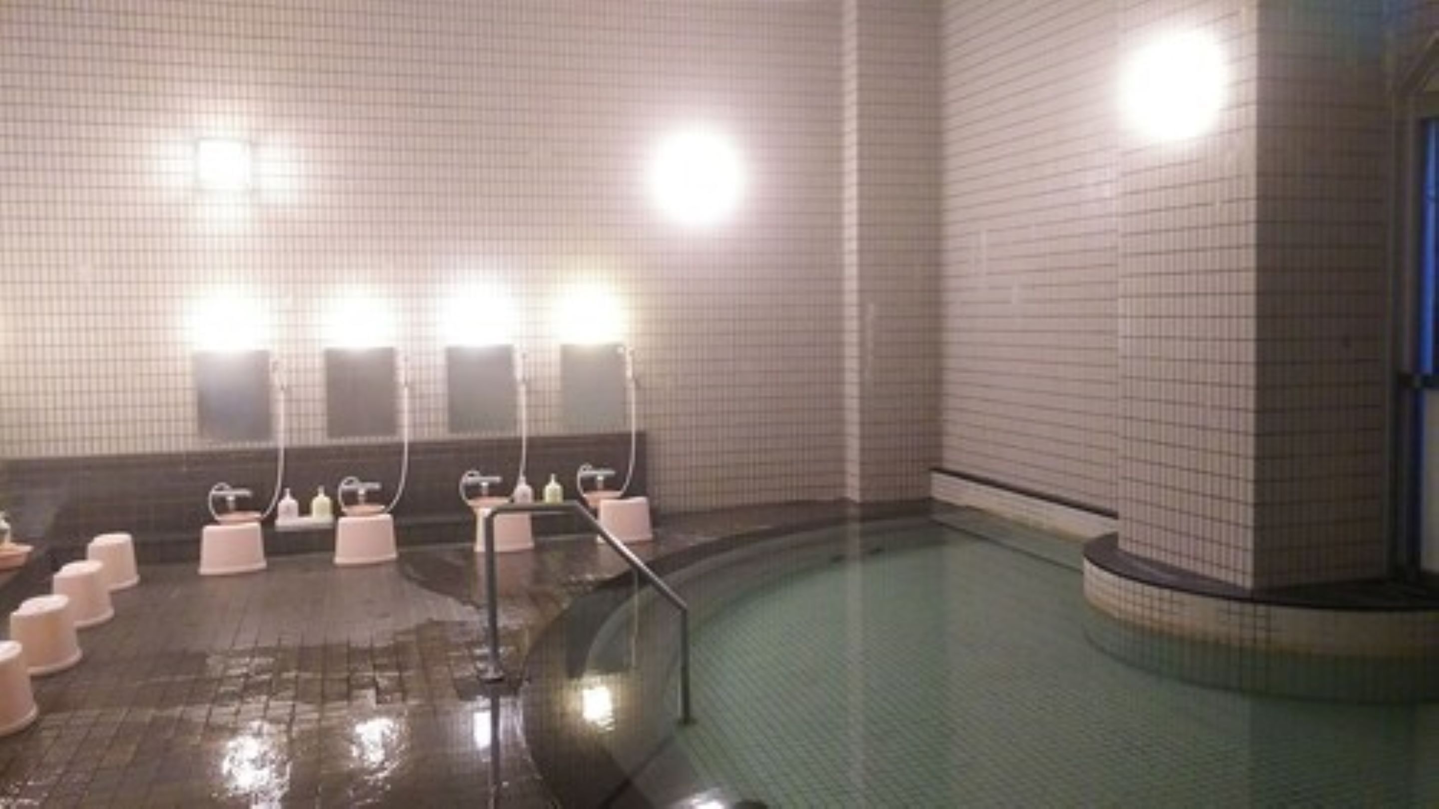 A public shower area with multiple sinks, hand dryers, and a tiled floor.