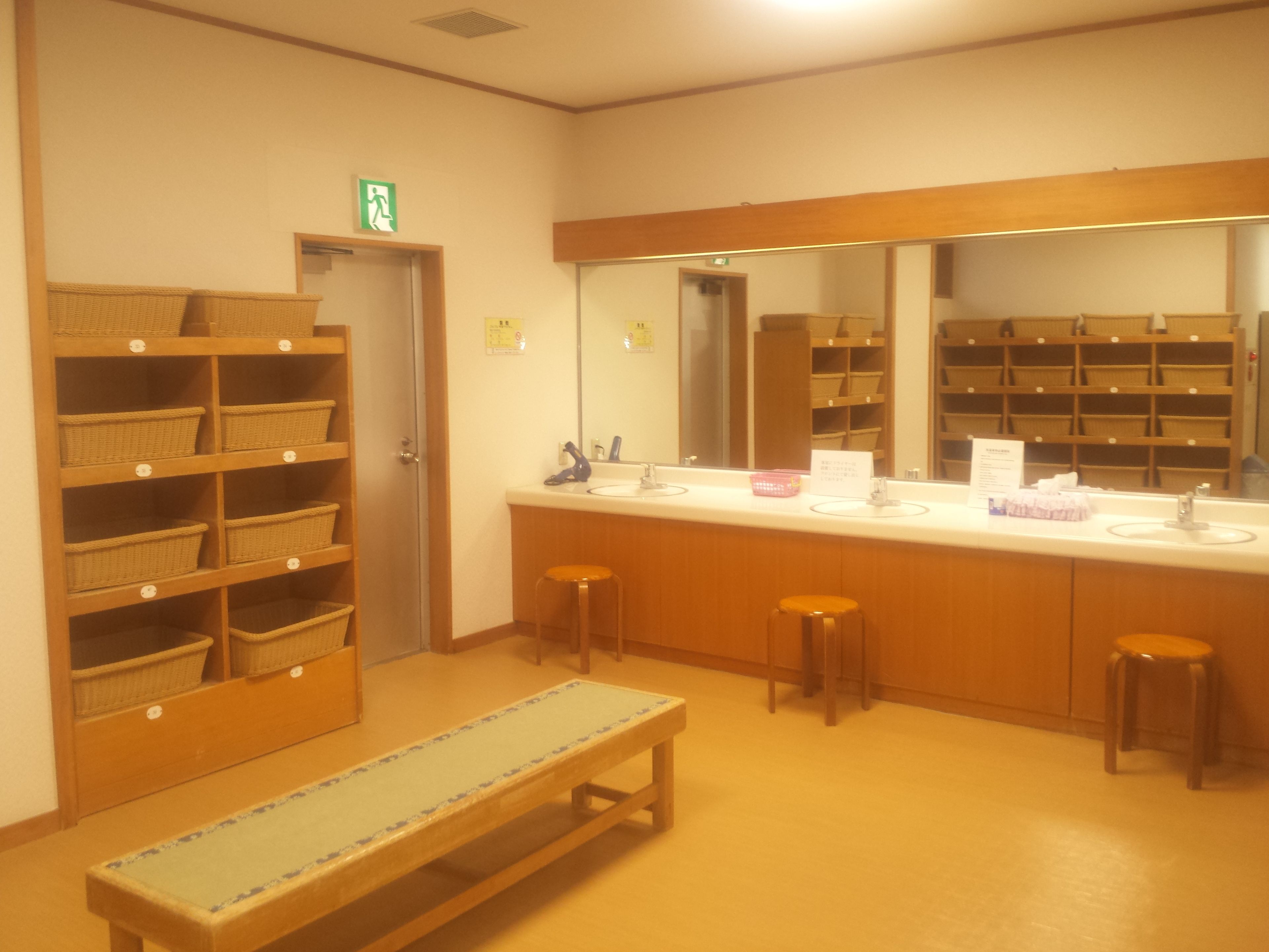 A bathroom with wooden shelves, a bench, and a large mirror.