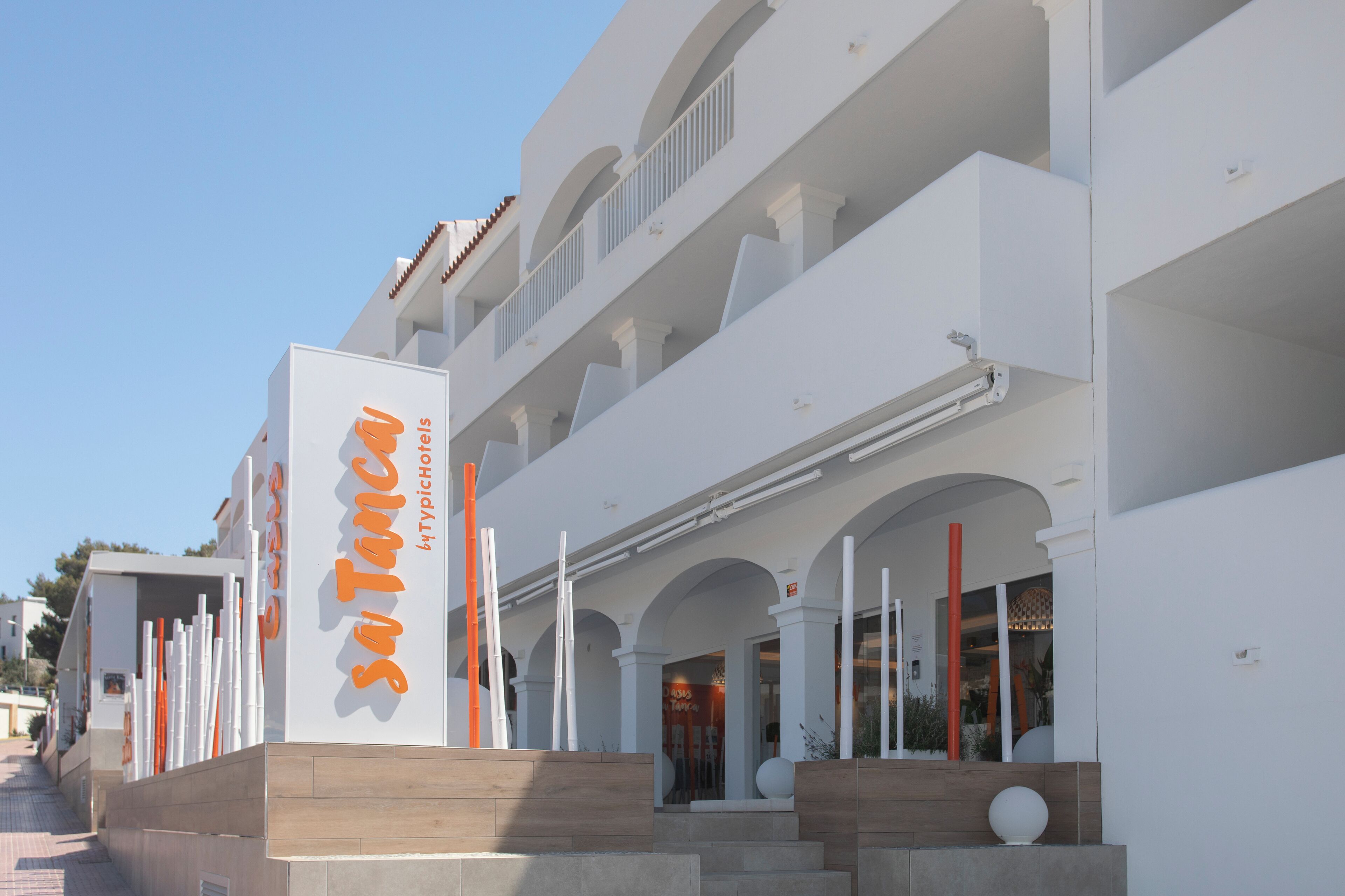 A modern hotel with a prominent sign, multiple balconies, and a clean architectural design.