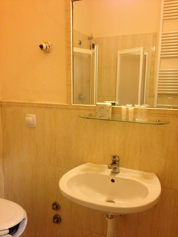 A bathroom with a white sink, a glass shelf above it, and a mirror reflecting the room. - Hotel Santa Costanza (San Vincenzo)