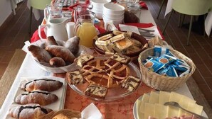 A breakfast buffet with pastries, bread, cheese, and ham. - Hotel Santa Costanza (San Vincenzo)