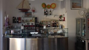 A kitchen with a stainless steel island, wine bottles on shelves, and a ship decoration on the wall. - Hotel Santa Costanza (San Vincenzo)