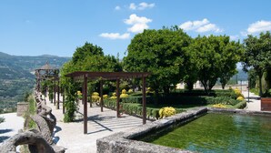 Un jardín con un sendero de piedra, una pérgola y un pequeño estanque.
