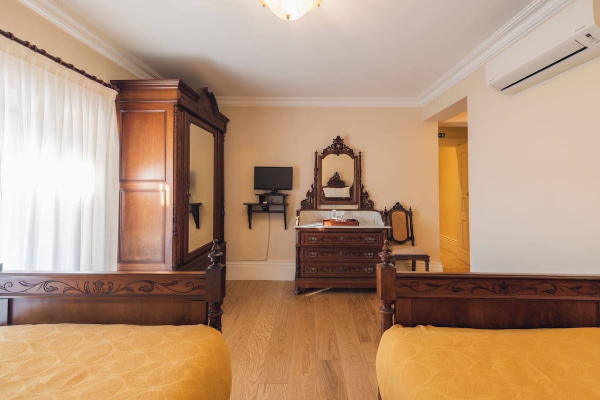 A hotel room with two beds, a wooden dresser, a television, and a mirror.