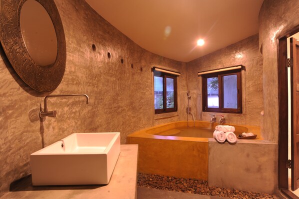 Un baño moderno con un lavamanos rectangular, una bañera independiente y dos ventanas.