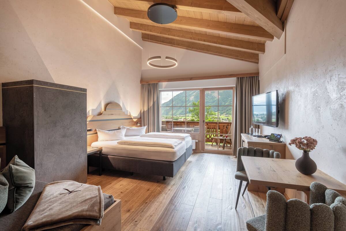 Una habitación de hotel moderna con una cama grande, un escritorio y una mesa de comedor.