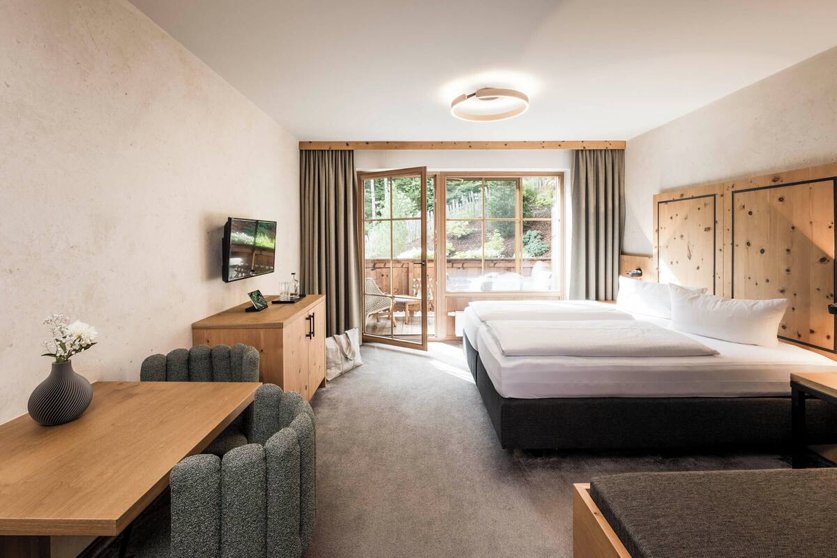 Habitación de hotel con una cama grande, un escritorio, un televisor y vistas al exterior.