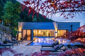 A modern house with a swimming pool, lounge chairs, and a view of a forested hillside. - Das Kaltenbach (Kaltenbach)