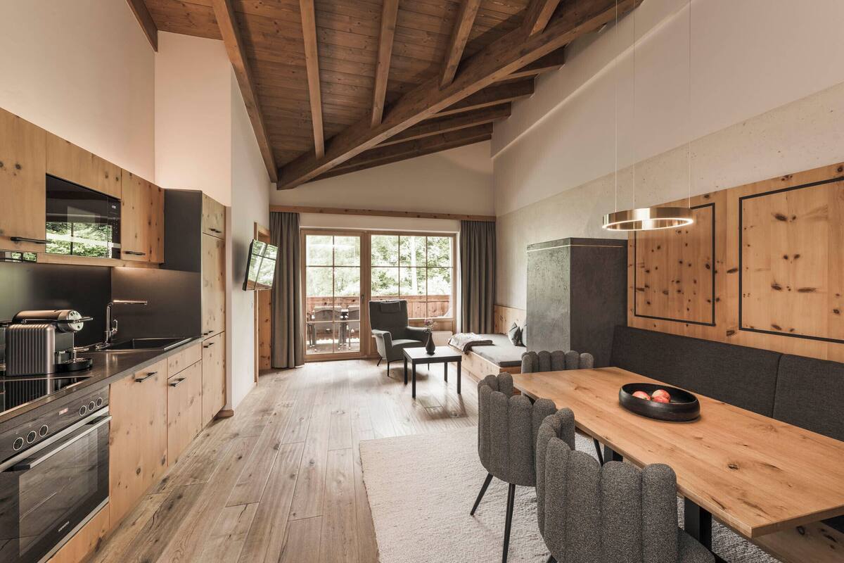 Una cocina moderna con armarios de madera, una isla grande y una zona de comedor con mesa y sillas de madera.