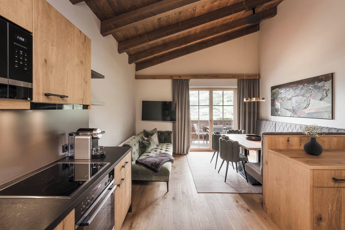 Una cocina moderna con armarios de madera, estufa integrada y un comedor con sofá y sillas.
