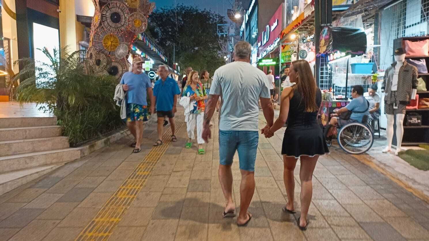 Une rue animée où l’on voit des passants, un fauteuil roulant et une horloge décorative.