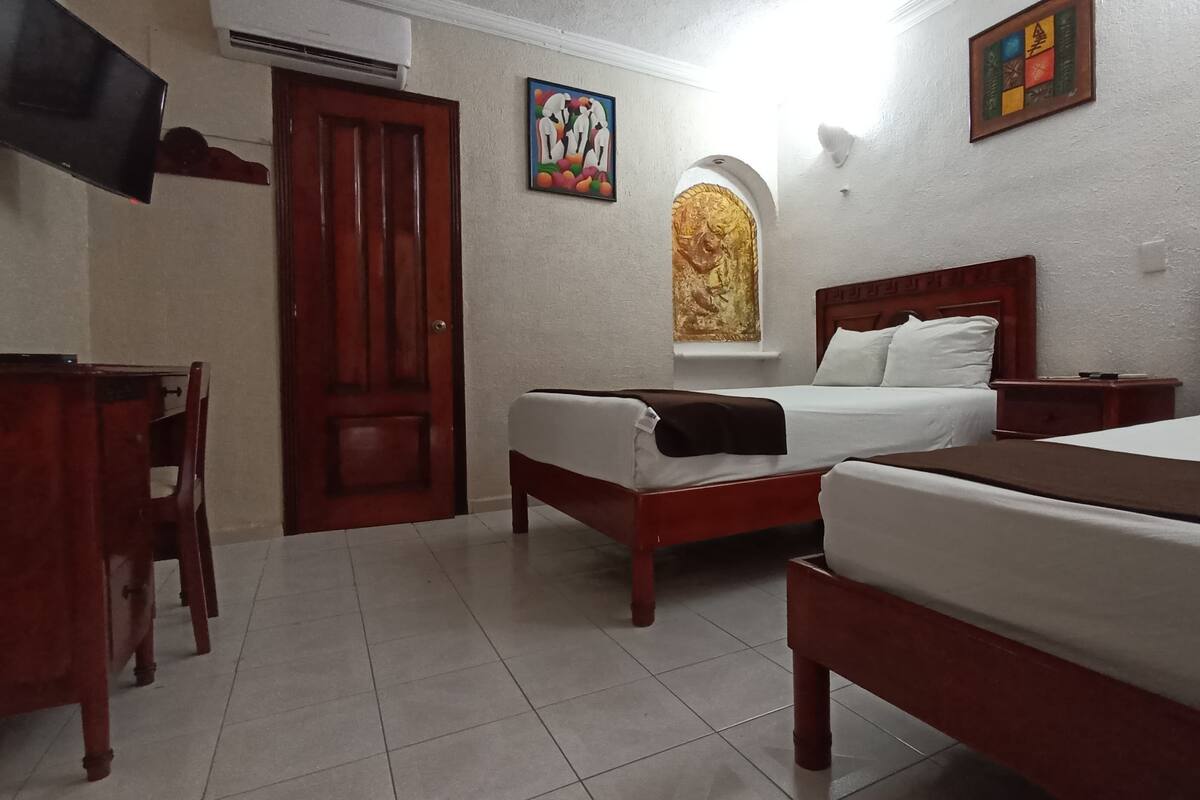 Una habitación de hotel con dos camas, un escritorio y una televisión.