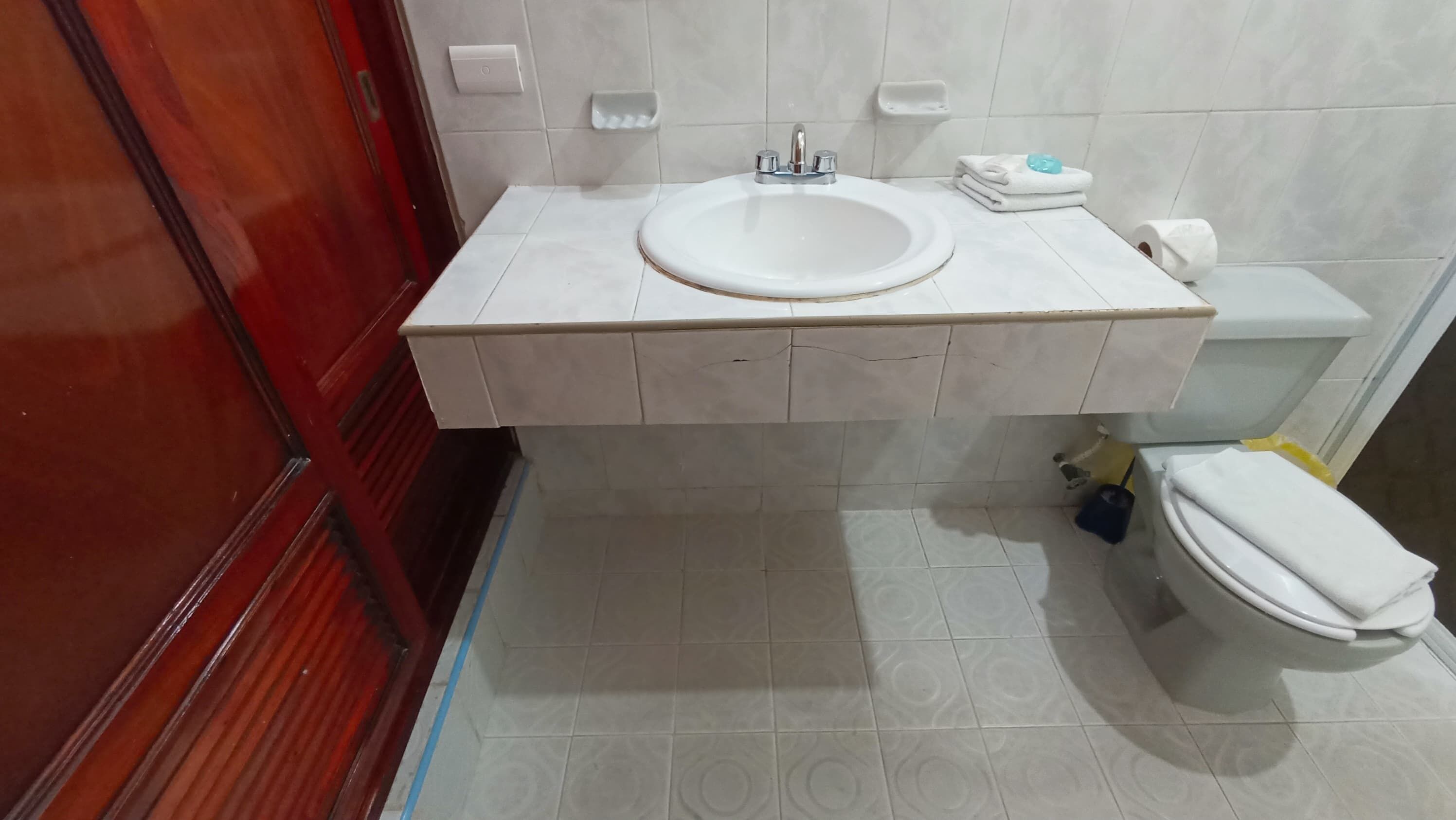 A bathroom with a white sink, toilet, and a red door.