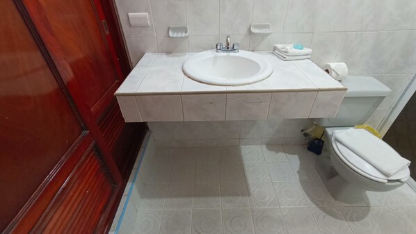 A bathroom with a white sink, toilet, and a red door. - Beach House Hotel (Playa del Carmen)