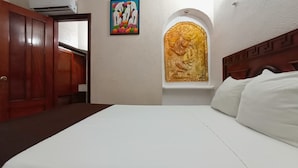 Una habitación de hotel con una cama, un armario de madera, un cuadro y un adorno en la pared.